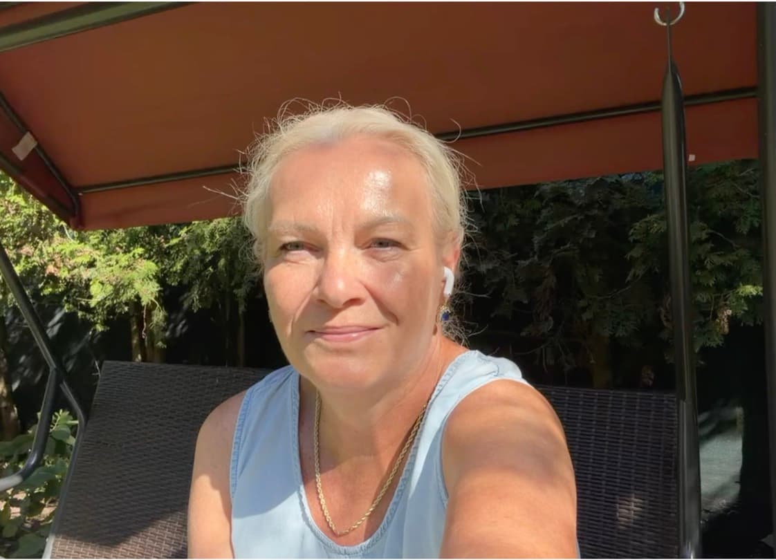 Jarka Matušková sedí na zahradní houpačce ve stínu markýzy, za ní zeleň, a s klidným úsměvem se dívá do objektivu.